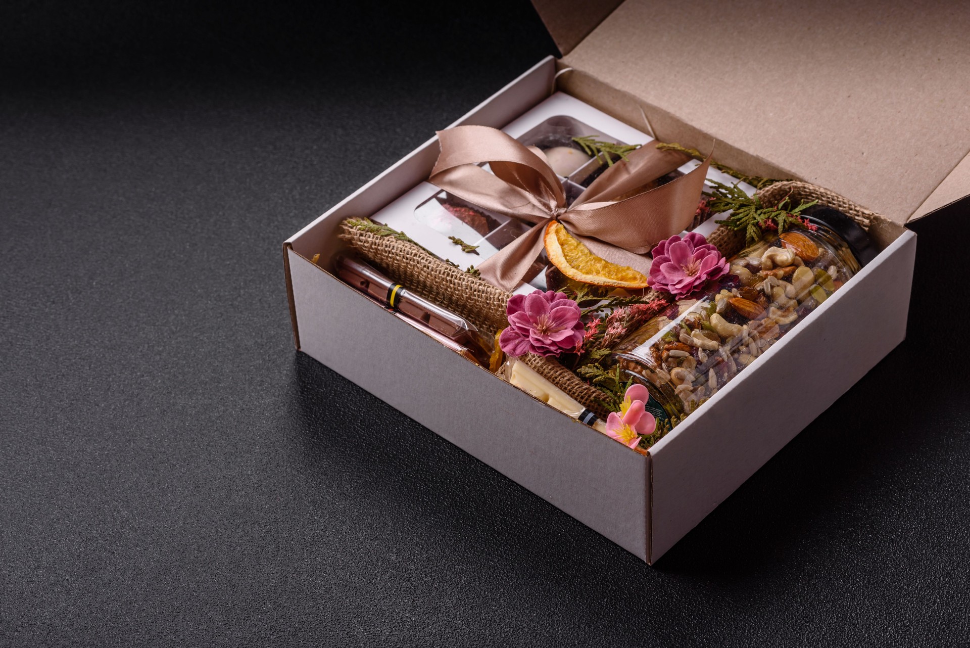 Gift box with a jar of nuts with honey, chocolate and craft candies